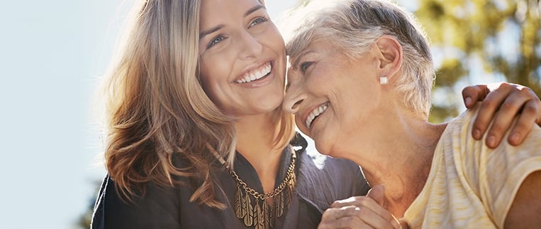 Older and younger woman wrapping their arms around one another