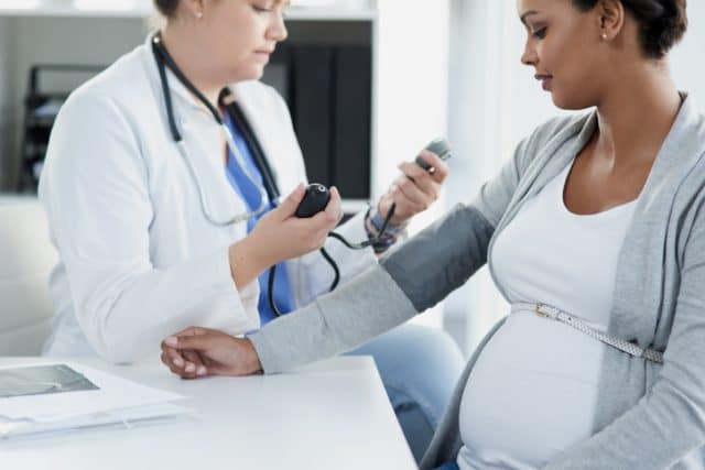 doctor checking blood pressure of pregnant woman