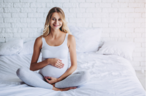 Attractive pregnant woman is sitting in bed