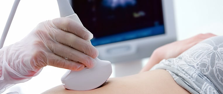 doctor performing ultrasound on woman’s stomach