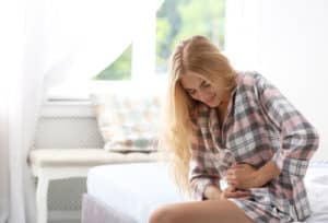 woman suffering from pain in bedroom.